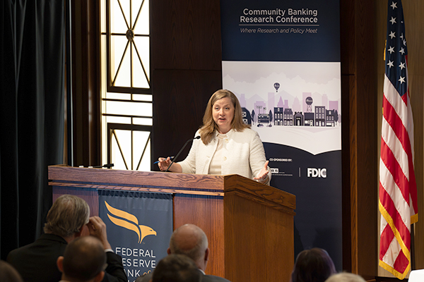 A woman at a podium presenting to an audience.