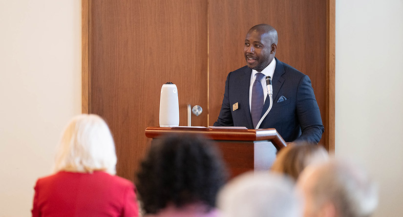 Man a podium addresses audience.