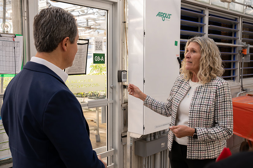 A woman speaks with Musalem in front of glass doors to a greenhouse.